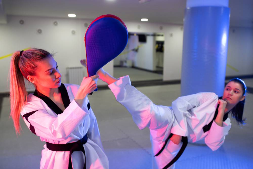2 taekwondo females kicking pads