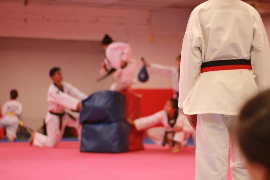 Taekwondo student standing back, watching the students practice in the gym.