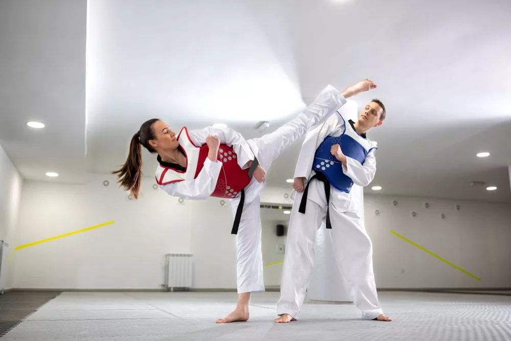 2 taekwondo players exchanging kicks